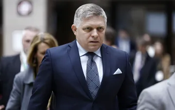 Прем'єр-міністр Словаччини Роберт Фіцо в костюмі та краватці йде коридором на міжнародній зустрічі