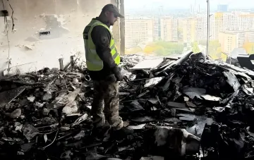 Рятувальник оглядає руйнування та уламки після нічного удару безпілотника по багатоповерховому будинку в Києві