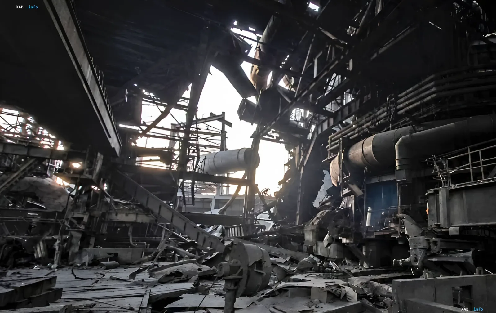 Destroyed hangar of a large metallurgical plant with twisted metal structures and equipment debris after shelling