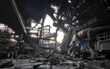 Destroyed hangar of a large metallurgical plant with twisted metal structures and equipment debris after shelling