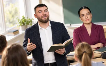 Teacher Artur Proydakov and a co-host speaking in a classroom during preparation for an educational event