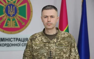 Спикер Государственной пограничной службы Украины Андрей Демченко в военной форме на фоне государственной символики