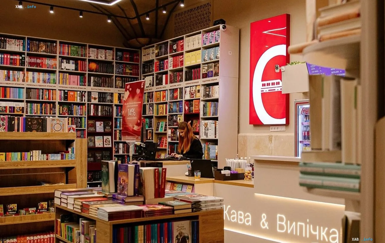 Интерьер книжного магазина Книгарня Е с полками, заставленными книгами, и продавцом за кассой