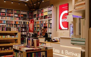 Інтер'єр книгарні Книгарня Є з полицями, заповненими книгами, та продавцем за касою