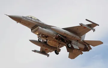 Военный истребитель F-16 в полете с ракетами и топливными баками под крыльями