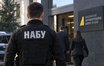 NABU officer in tactical gear in front of the National Anti-Corruption Bureau of Ukraine building