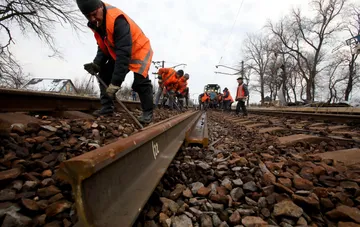 Рабочие в оранжевых жилетах проводят ремонт железнодорожных путей
