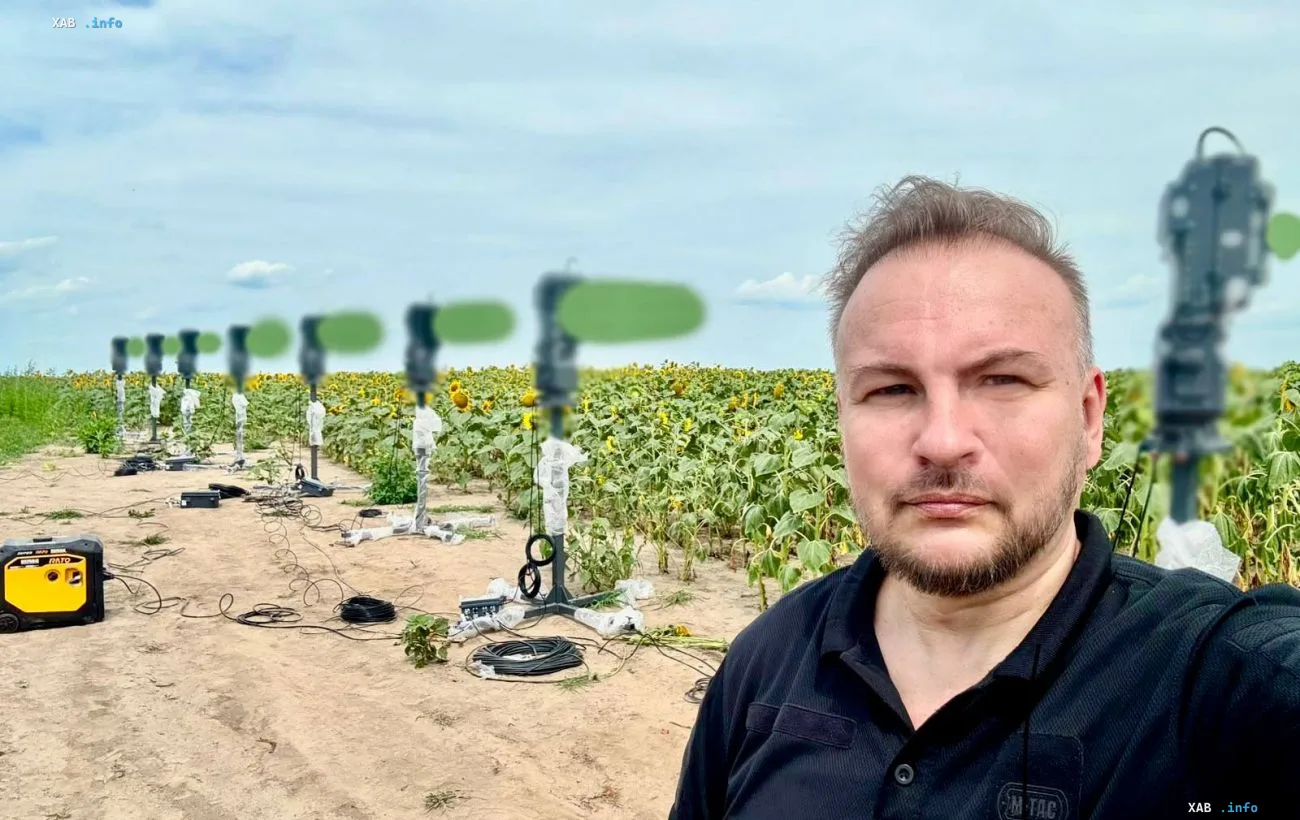 Mann vor einem Sonnenblumenfeld mit Feldkommunikationsgeräten und Antennen unter dem Himmel
