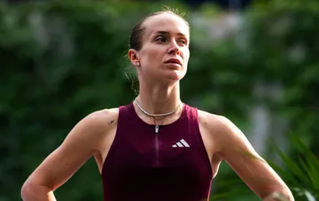 Элина Свитолина в спортивной бордовой форме на фоне зеленой изгороди во время интервью