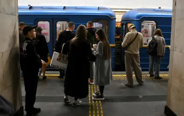 Fahrgäste warten an einer U-Bahn-Station der Hauptstadt auf einen Zug vor blauen Waggons