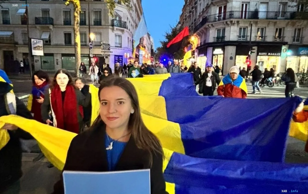 Група людей з українським прапором на вулиці Парижа під час мітингу на підтримку України