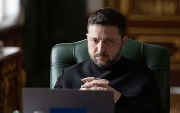 Президент України Володимир Зеленський сидить за робочим столом у темному светрі під час відеозв'язку.