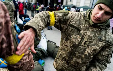 Украинский военнослужащий в камуфляжной форме проверяет шеврон во время мобилизационных мероприятий