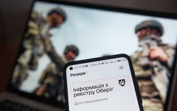 Смартфон з відкритим додатком Резерв+ на фоні ноутбука з військовими