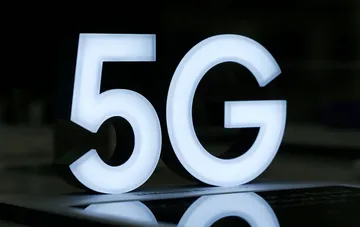 Светящийся белый знак 5G на темном фоне демонстрирует развитие мобильных технологий связи