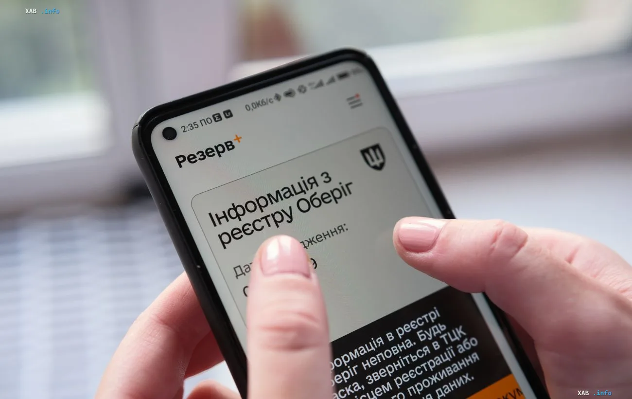 Смартфон с открытым приложением Резерв+ в руках человека