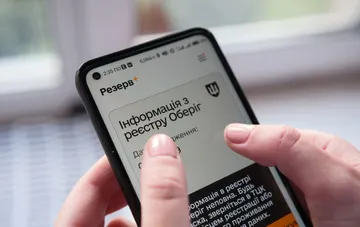 Смартфон с открытым приложением Резерв+ в руках человека