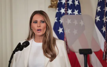 Перша леді США Меланія Трамп виступає під час офіційного заходу на тлі американських прапорів