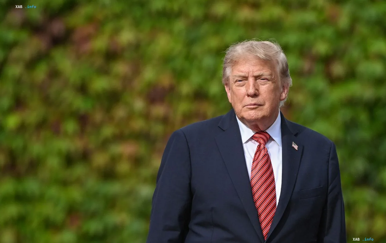 Президент США Дональд Трамп в костюме и галстуке на фоне зеленой изгороди