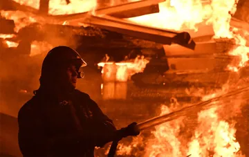 Ein Feuerwehrmann in Schutzkusrüstung löscht einen Großbrand in einer Industrieanlage
