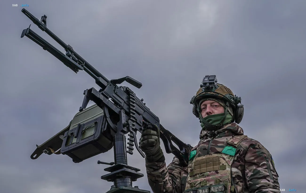 Украинский военнослужащий в экипировке у пулеметной установки крупным планом во время боевого дежурства