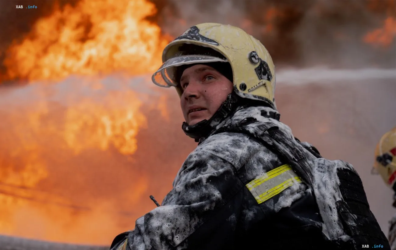 Пожарный в защитном шлеме и форме наблюдает за тушением масштабного пожара в Харькове