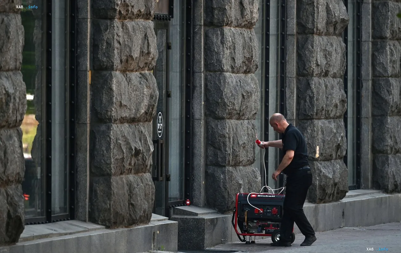 A man connects a portable generator on the street near a stone building in Kyiv
