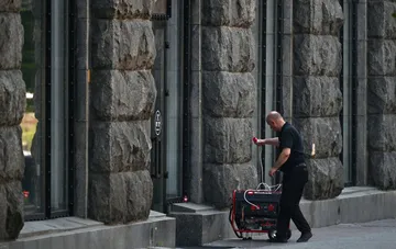 A man connects a portable generator on the street near a stone building in Kyiv
