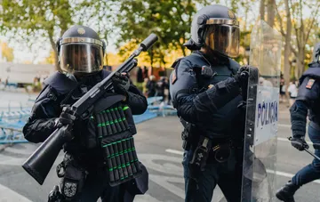 Екіпіровані іспанські поліцейські в захисних шоломах та зі щитом під час охорони порядку на вулиці Барселони