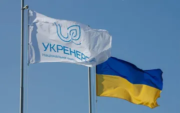 Flaggen von NEC Ukrenergo und der Ukraine vor dem Hintergrund eines klaren Himmels