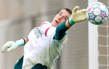 Torhüter von Real Madrid in Handschuhen springt, um einen Fußball im Training zu parieren