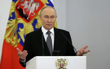 Президент России Владимир Путин выступает за трибуной перед государственным флагом