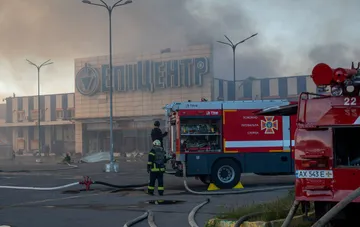 Fire engines working near the damaged facade of an Epicenter shopping center after a strike