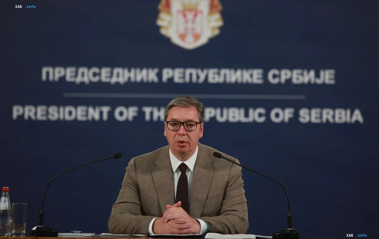 Бывший президент Сербии Александр Вучич выступает на пресс-конференции перед синим фоном с государственным гербом.