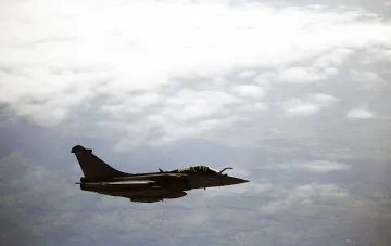 Французский истребитель Rafale в полете над облаками и ландшафтом