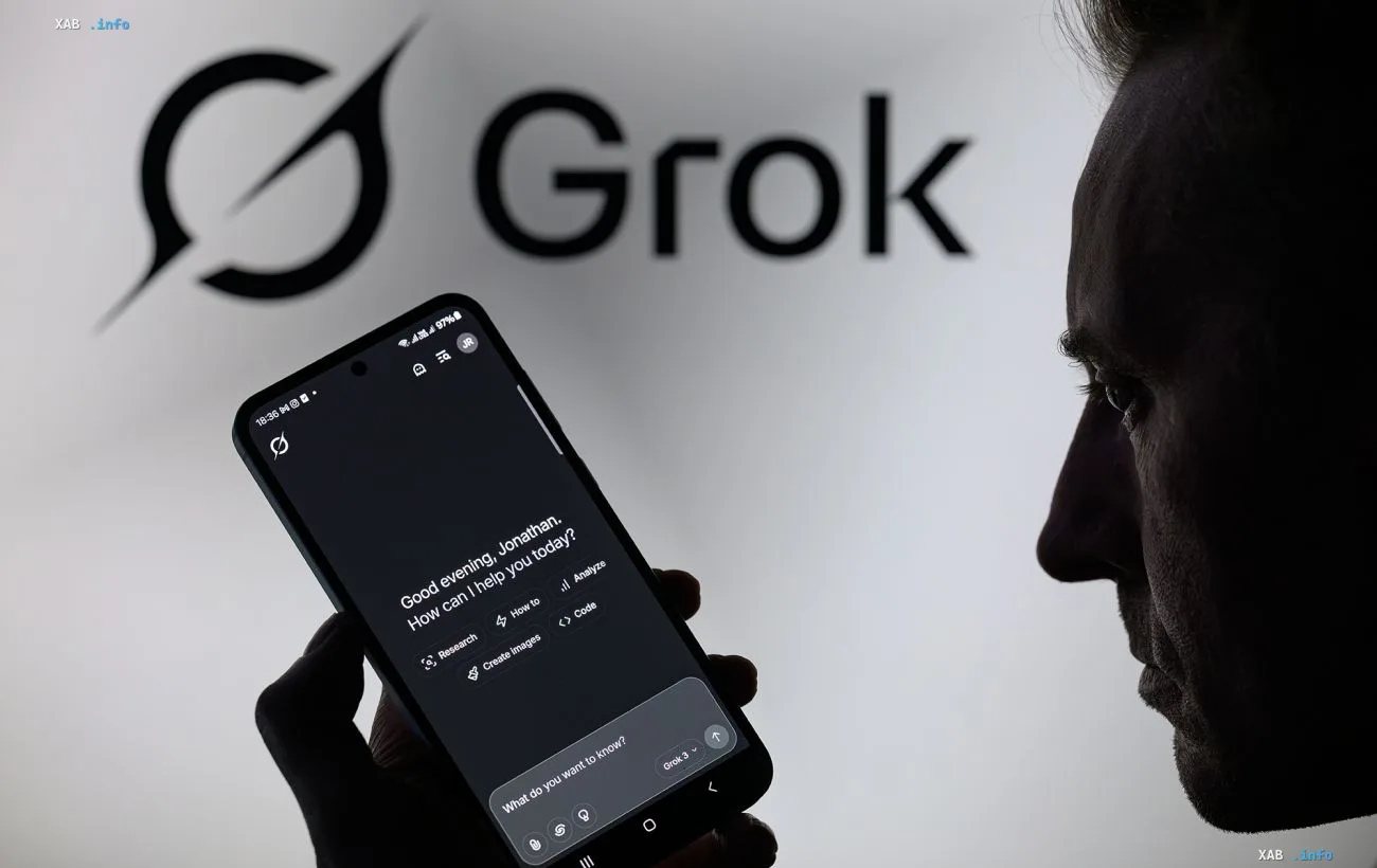 Мужчина смотрит на экран смартфона с чат-ботом Grok и логотипом компании на фоне