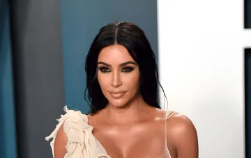 Kim Kardashian mit dunklen Haaren und Abend-Make-up auf dem roten Teppich in einem hellen Outfit