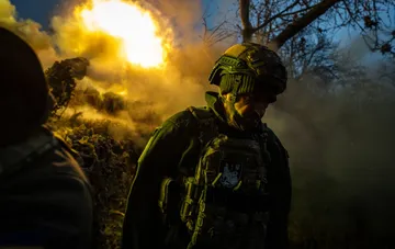Военнослужащий ВСУ в защитной экипировке на фоне взрыва и дыма на фронте