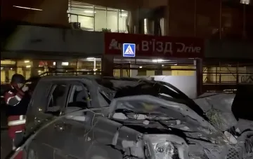 Destroyed car in front of the damaged Auchan store building in Kyiv following the attack