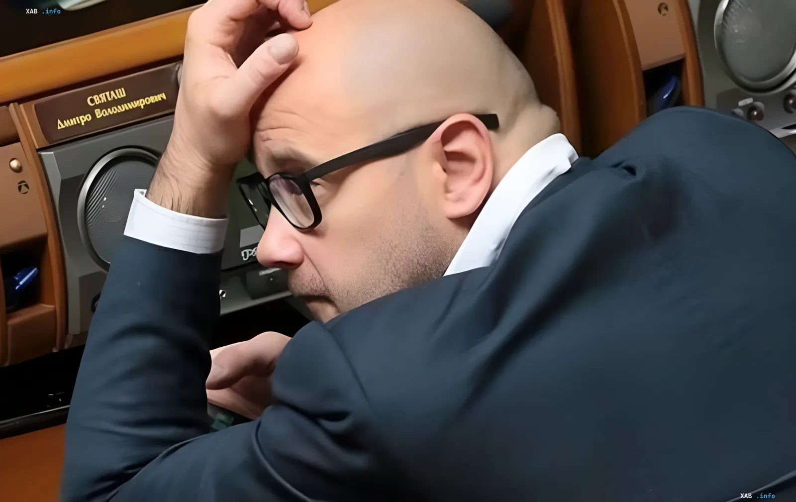 Чоловік у окулярах сидить за столом і тримається за голову під час засідання в українському парламенті