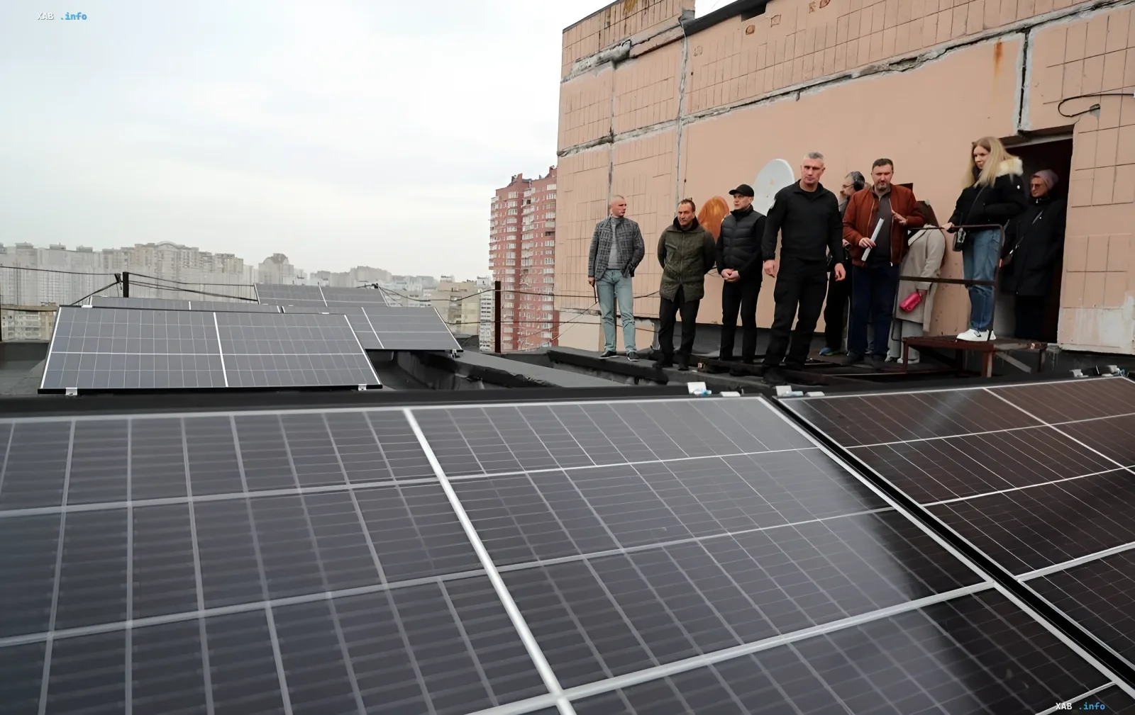 Vitali Klitschko with a group of people inspects solar panels on a residential roof in Kyiv
