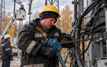 Робітник у касці ремонтує пошкоджені кабельні лінії на енергетичному об'єкті