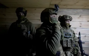 Ukrainian soldiers in full combat gear inside a fortified room