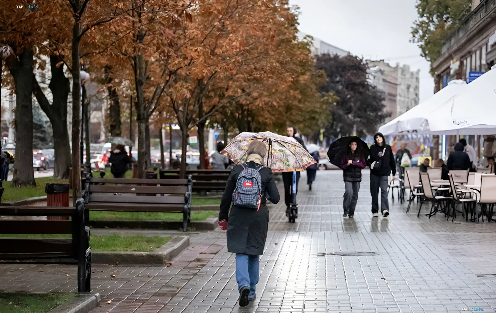 Люди с зонтами идут по мокрому осеннему тротуару в Киеве во время дождя