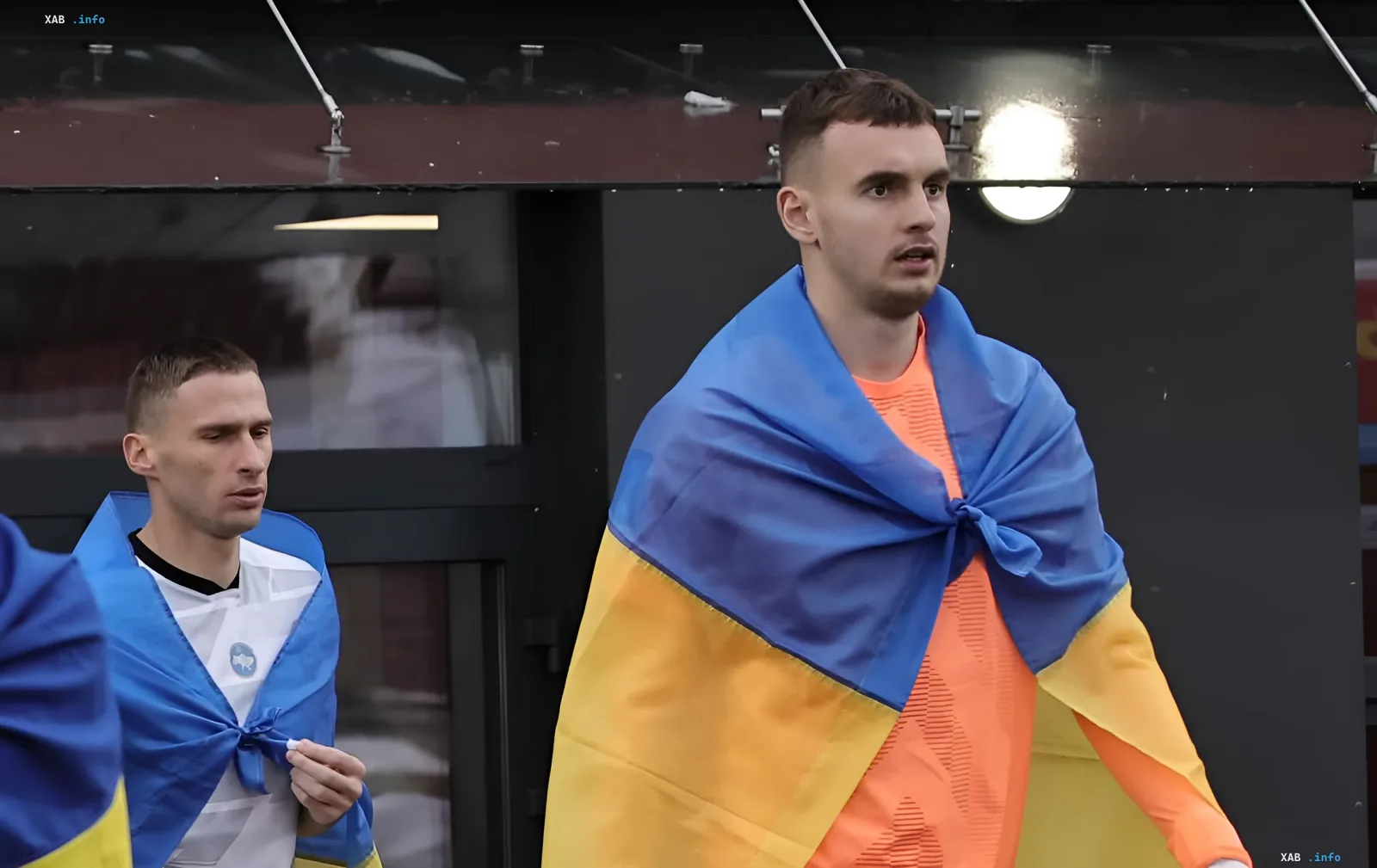 Fussballspieler im orangen Trikot mit der ukrainischen Flagge auf den Schultern im Stadion