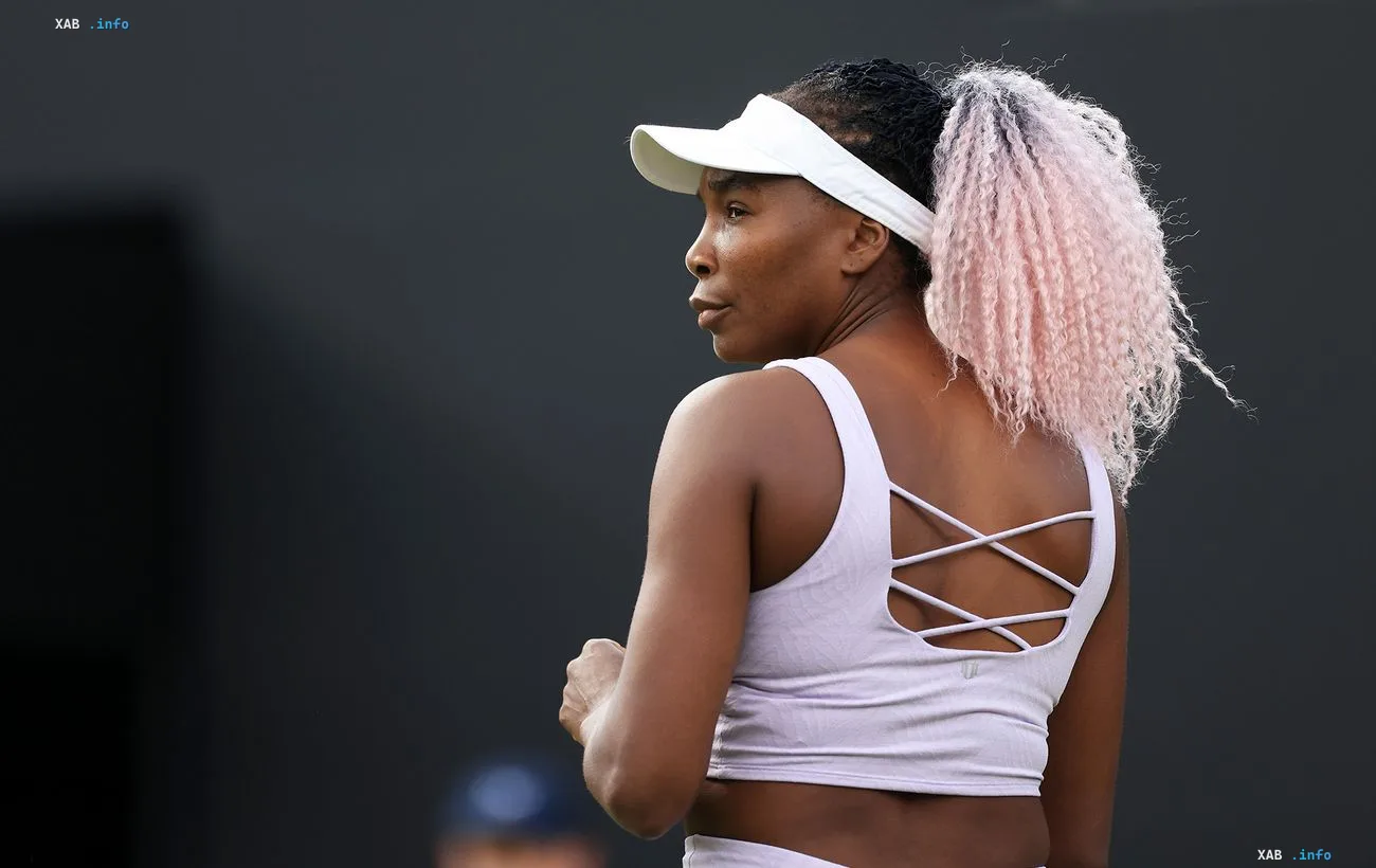 Tennis player Venus Williams on court wearing a white visor and pink hair