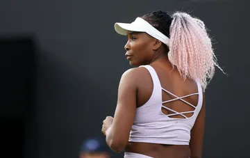 Tennis player Venus Williams on court wearing a white visor and pink hair