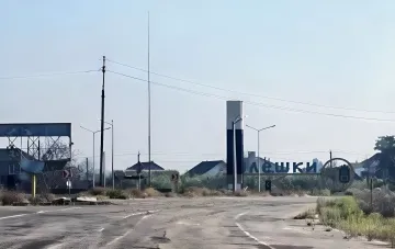 Дорожный указатель с надписью Олешки на фоне разрушенной инфраструктуры и выжженной земли