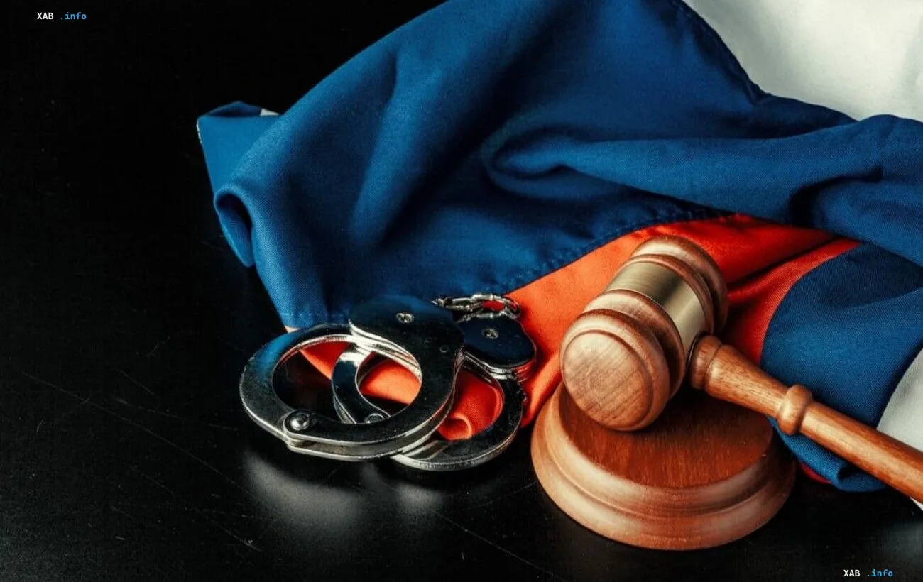 Судівний молоток та кайданки на тлі прапора на столі в суді