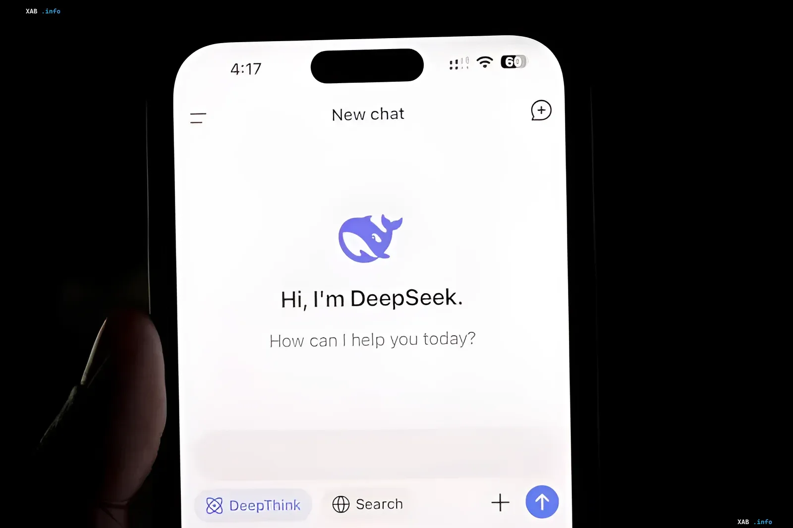 Смартфон в руке с запущенным интерфейсом чат-бота DeepSeek в темноте